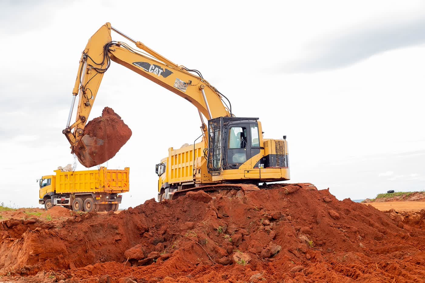 Ellyz excavator loading red laterite into a tipper truck on a Tanzanian earthworks site