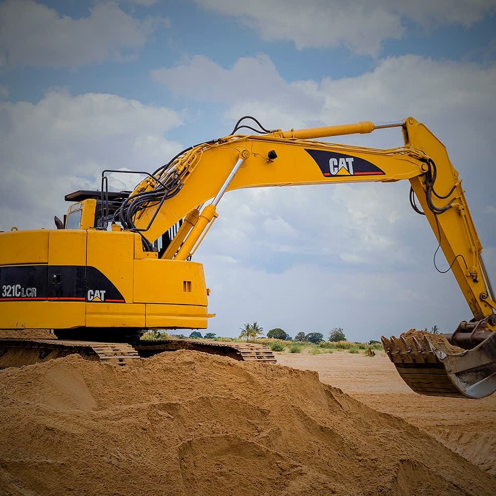 Ellyz excavator lifting a bucket of laterite over a tipper truck